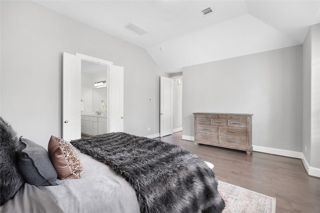 bedroom with connected bathroom, vaulted ceiling, and dark hardwood / wood-style flooring