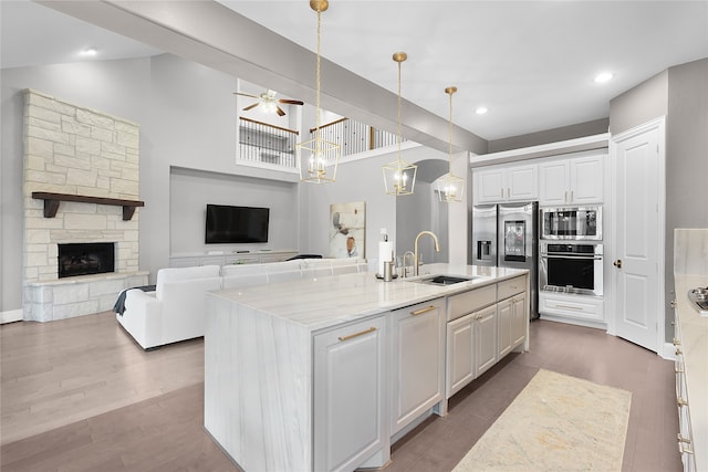 kitchen featuring appliances with stainless steel finishes, white cabinetry, a kitchen island with sink, and sink