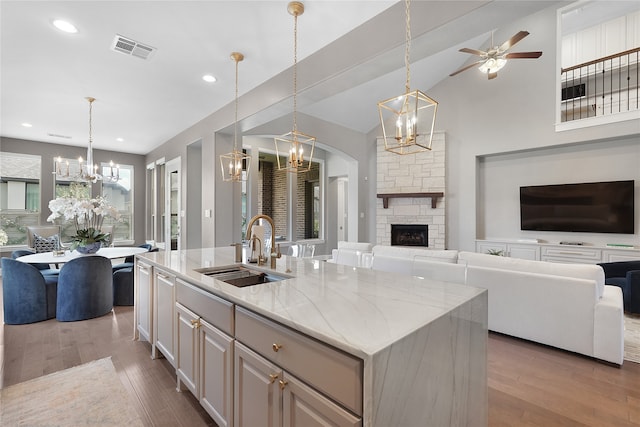 kitchen featuring pendant lighting, wood-type flooring, sink, and an island with sink