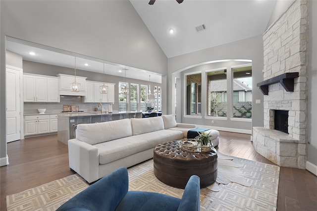 living room with light hardwood / wood-style flooring, sink, a fireplace, high vaulted ceiling, and ceiling fan