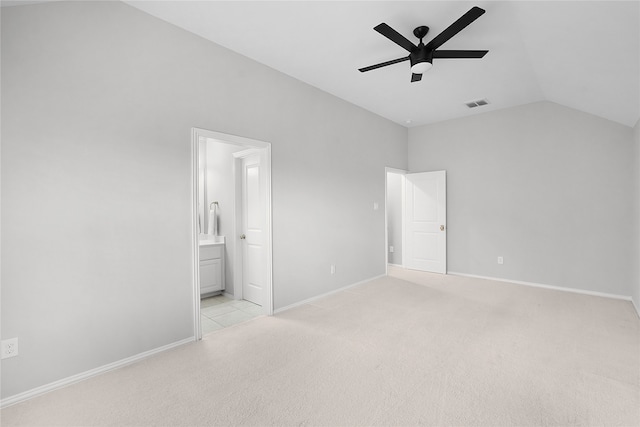 unfurnished bedroom featuring light carpet, vaulted ceiling, ceiling fan, and ensuite bath