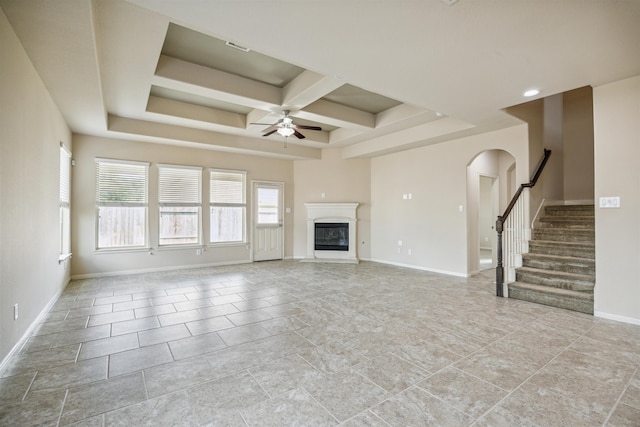 unfurnished living room with beam ceiling, plenty of natural light, coffered ceiling, and ceiling fan