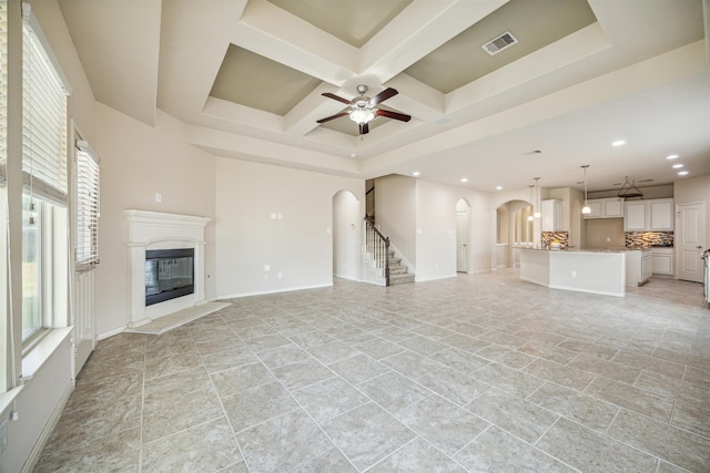 unfurnished living room with beamed ceiling, ceiling fan, and coffered ceiling