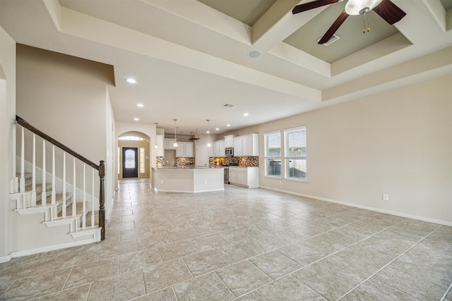 unfurnished living room with a wealth of natural light and ceiling fan