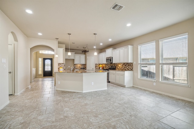 kitchen with sink, hanging light fixtures, backsplash, white cabinets, and appliances with stainless steel finishes