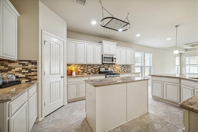 kitchen with decorative backsplash, a center island, white cabinetry, and appliances with stainless steel finishes