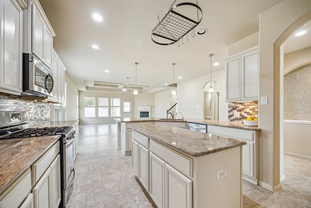 kitchen featuring decorative backsplash, decorative light fixtures, stainless steel appliances, and a kitchen island