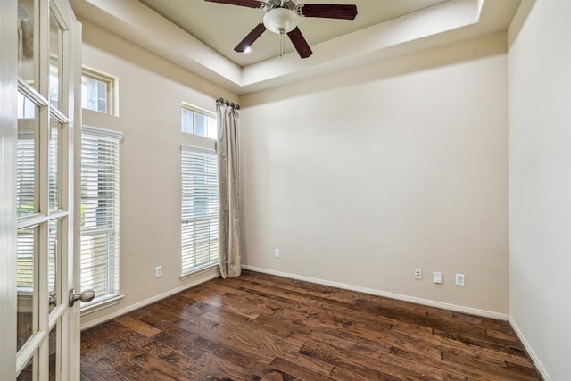 empty room featuring dark hardwood / wood-style flooring, a raised ceiling, and ceiling fan