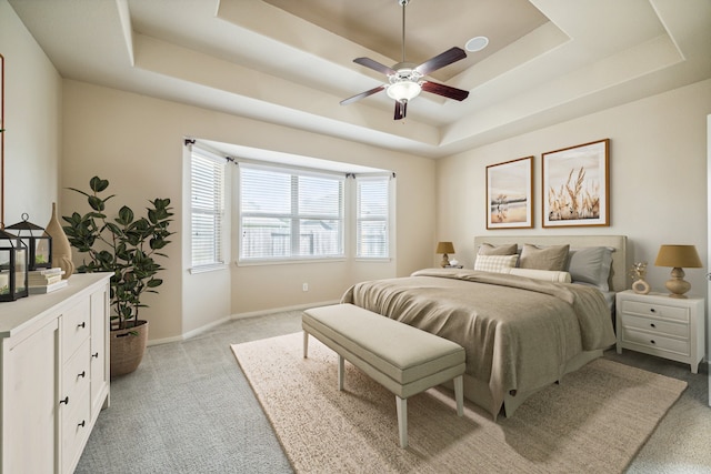 carpeted bedroom featuring a raised ceiling and ceiling fan