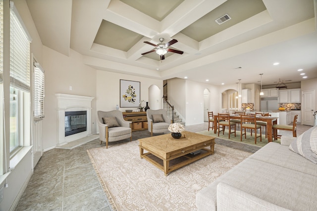 living room featuring beam ceiling, ceiling fan, and coffered ceiling