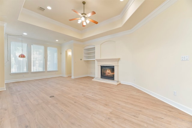 unfurnished living room with light hardwood / wood-style floors, a tray ceiling, crown molding, and ceiling fan