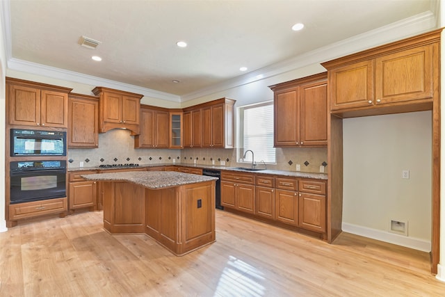 kitchen featuring black appliances, a center island, sink, and light hardwood / wood-style flooring