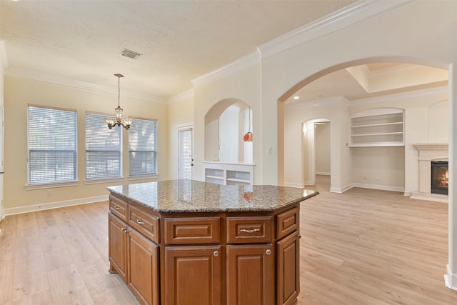 kitchen featuring a kitchen island, light wood-type flooring, a healthy amount of sunlight, and hanging light fixtures