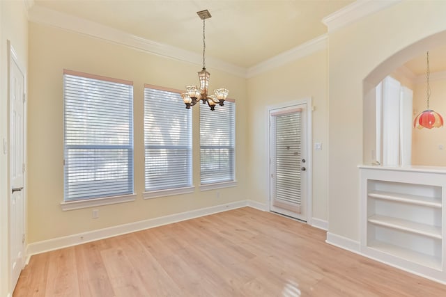 unfurnished room with a wealth of natural light, ornamental molding, a chandelier, and light wood-type flooring