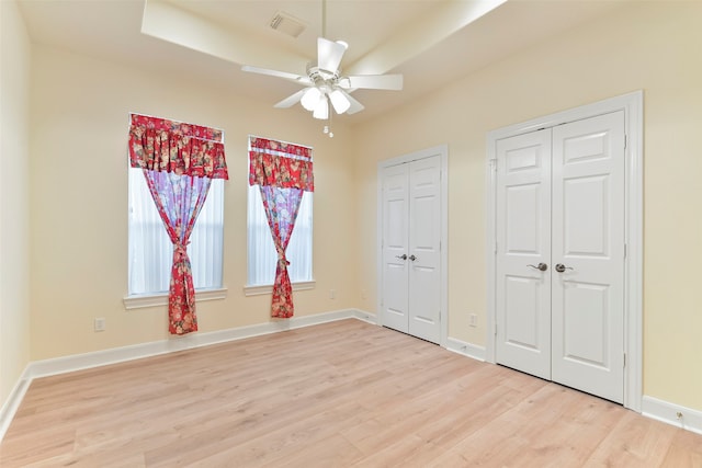 unfurnished bedroom featuring multiple closets, ceiling fan, and light wood-type flooring