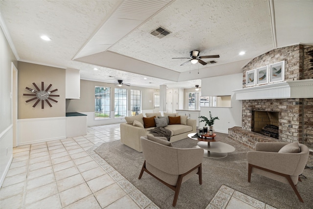 tiled living room with a textured ceiling, a brick fireplace, ceiling fan, and crown molding