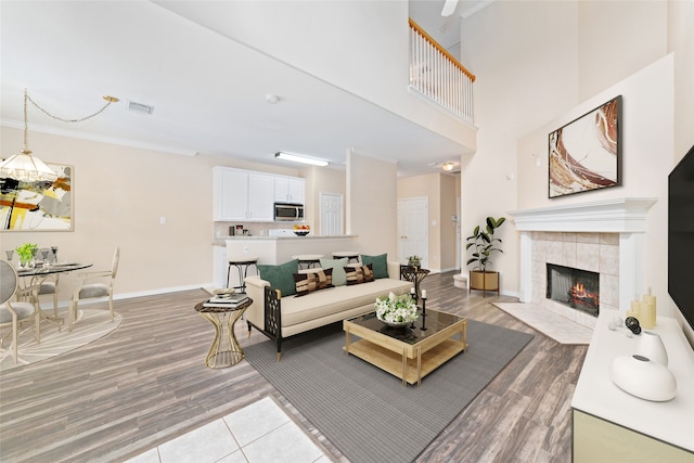 living room featuring ornamental molding, light hardwood / wood-style flooring, and a tiled fireplace