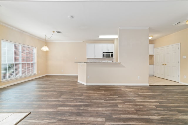 unfurnished living room featuring ornamental molding and dark wood-type flooring