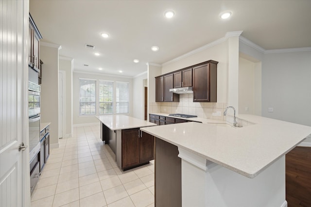 kitchen featuring tasteful backsplash, kitchen peninsula, crown molding, and light tile patterned floors