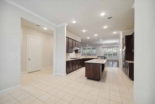 kitchen featuring black gas cooktop, a center island, dark brown cabinets, and ornamental molding