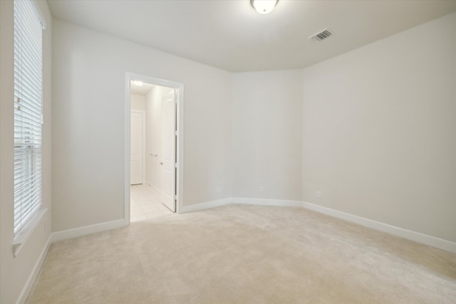 unfurnished room featuring light colored carpet and a healthy amount of sunlight