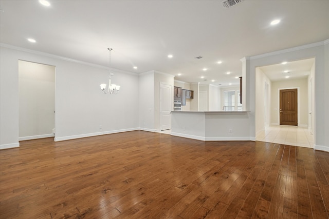 unfurnished living room with a chandelier, hardwood / wood-style flooring, and ornamental molding