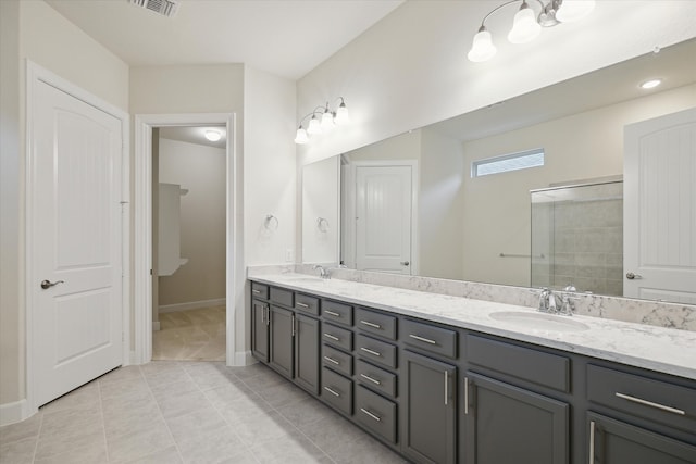 bathroom with a shower with door, vanity, and tile patterned flooring