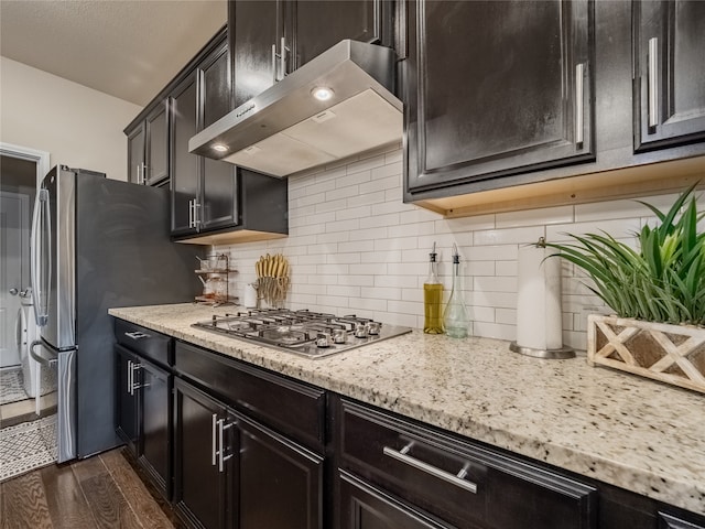 kitchen with tasteful backsplash, dark hardwood / wood-style flooring, extractor fan, light stone countertops, and stainless steel appliances