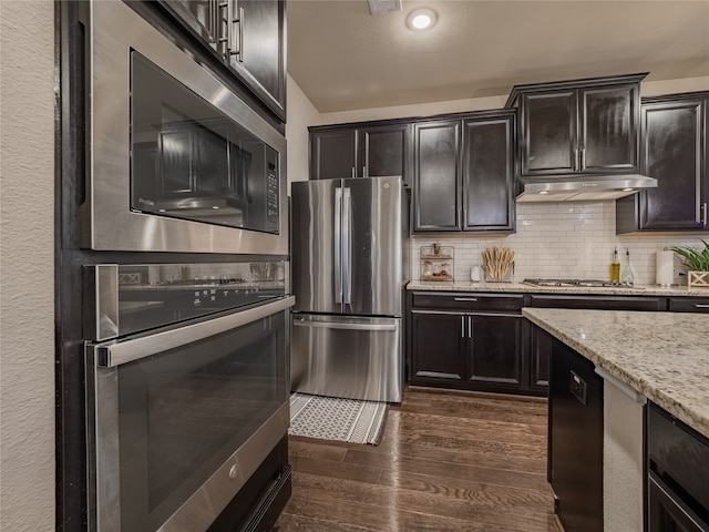 kitchen featuring decorative backsplash, light stone counters, stainless steel appliances, and dark hardwood / wood-style flooring