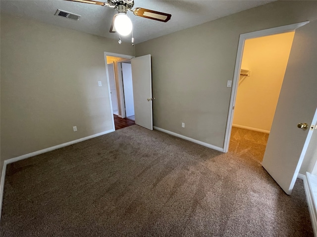 unfurnished bedroom with carpet, ceiling fan, a spacious closet, and a closet