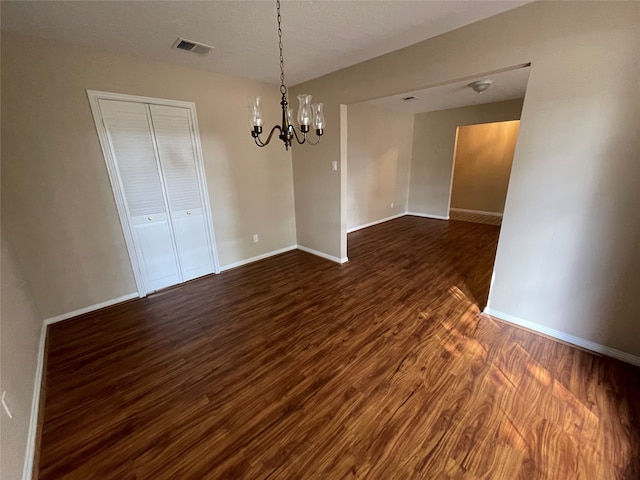 unfurnished dining area featuring a notable chandelier, dark hardwood / wood-style floors, and a textured ceiling