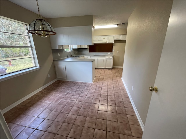 kitchen with sink, light tile patterned floors, an inviting chandelier, white cabinetry, and hanging light fixtures