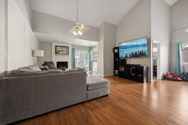 living room featuring light hardwood / wood-style flooring, a brick fireplace, high vaulted ceiling, and ceiling fan