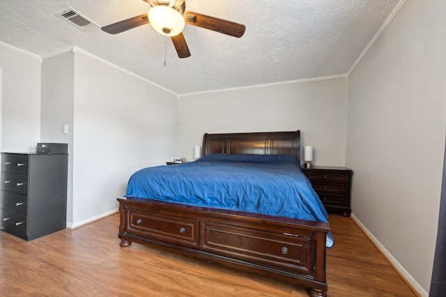 bedroom with lofted ceiling, ceiling fan, a textured ceiling, light wood-type flooring, and crown molding