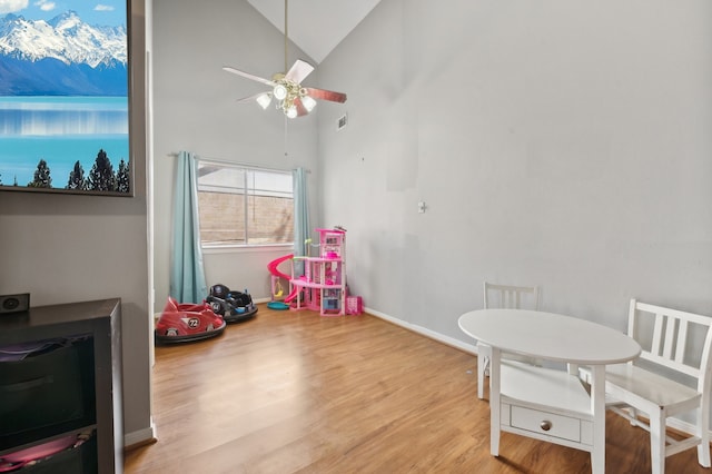 game room with light hardwood / wood-style floors, high vaulted ceiling, and ceiling fan