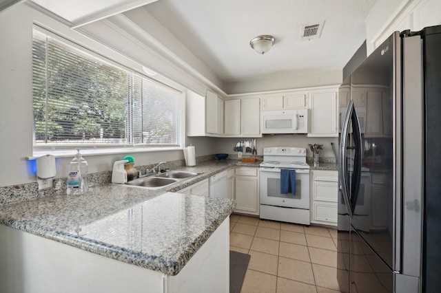 kitchen with white appliances, sink, kitchen peninsula, white cabinets, and light tile patterned floors