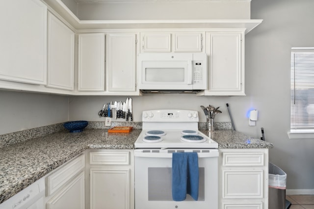 kitchen with white appliances, light stone counters, tile patterned floors, and white cabinets