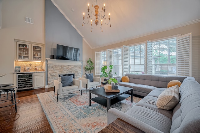 living room featuring beverage cooler, an inviting chandelier, dark wood-type flooring, a fireplace, and crown molding