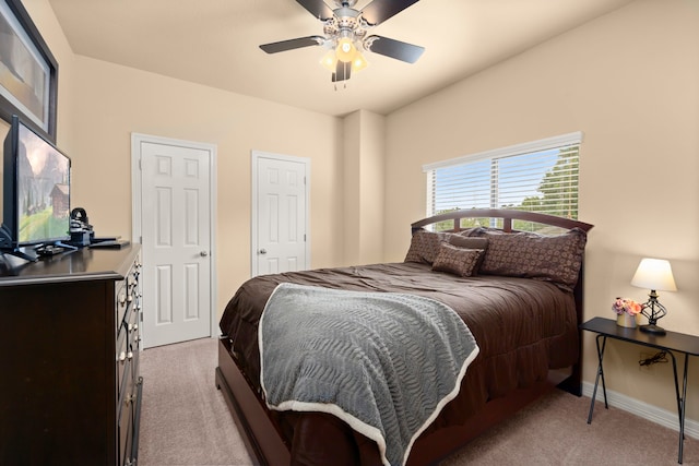 carpeted bedroom featuring multiple closets and ceiling fan