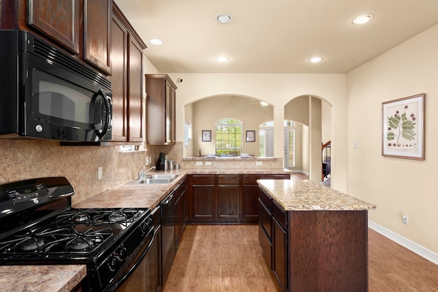 kitchen featuring black appliances, sink, kitchen peninsula, decorative backsplash, and light hardwood / wood-style flooring