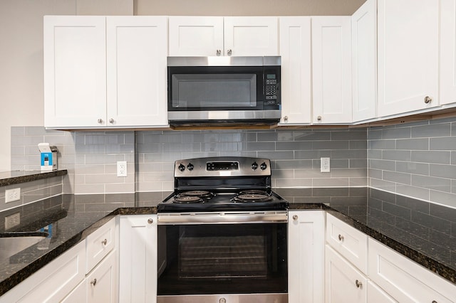 kitchen featuring white cabinets, tasteful backsplash, stainless steel appliances, and dark stone counters