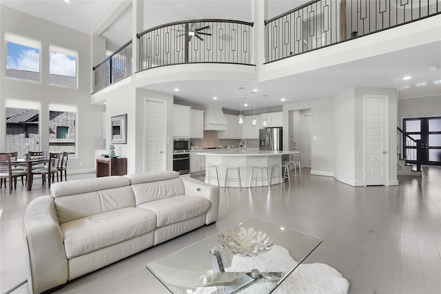 living room featuring sink, a high ceiling, and light hardwood / wood-style floors