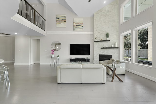 living room with a stone fireplace, wood-type flooring, and high vaulted ceiling