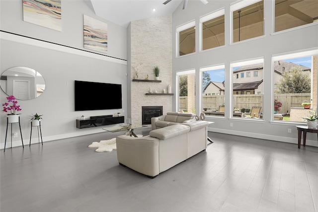 living room with a stone fireplace, hardwood / wood-style flooring, high vaulted ceiling, and ceiling fan