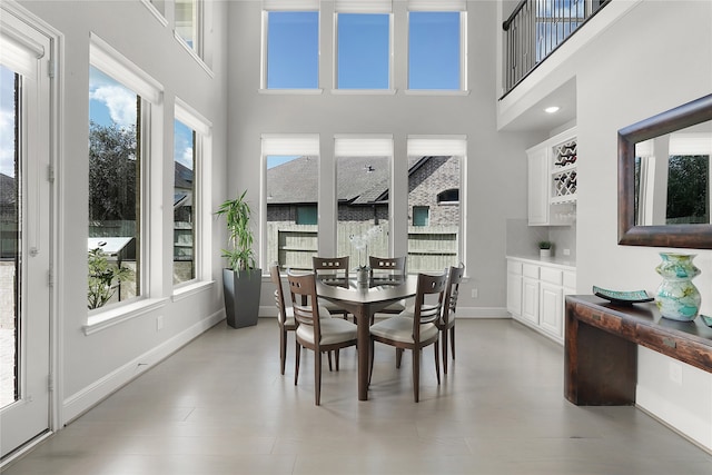 dining space featuring a towering ceiling and light wood-type flooring