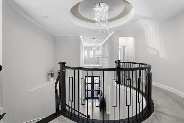 staircase featuring carpet, a notable chandelier, ornamental molding, and a tray ceiling