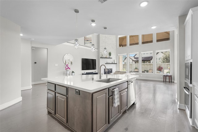 kitchen with dark hardwood / wood-style floors, dark brown cabinetry, sink, and a center island with sink