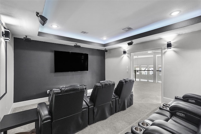 home theater room with light colored carpet and a tray ceiling