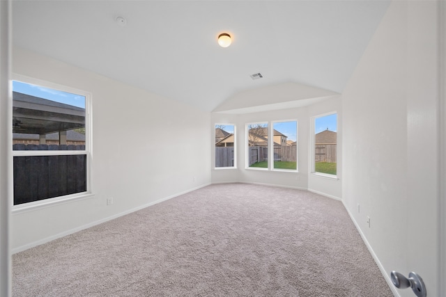 carpeted empty room with vaulted ceiling