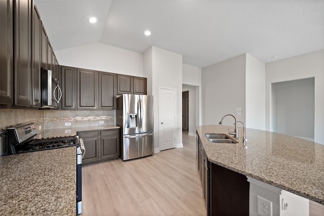 kitchen featuring light stone countertops, sink, light hardwood / wood-style flooring, vaulted ceiling, and appliances with stainless steel finishes